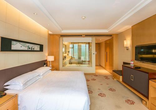 Sheraton Wuxi Binhu Hotel في ووشي: غرفة نوم بسرير كبير وتلفزيون بشاشة مسطحة