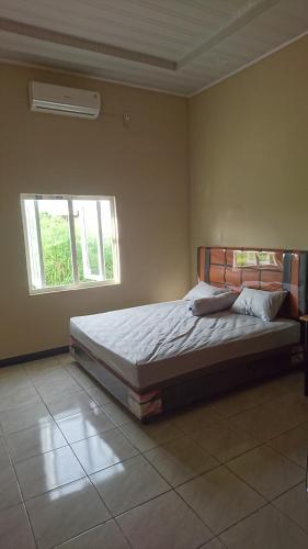1 dormitorio con 1 cama en una habitación con ventana en Unterkunft in der Nähe des Flughafens Kuala Namu Medan en Kampungbesar