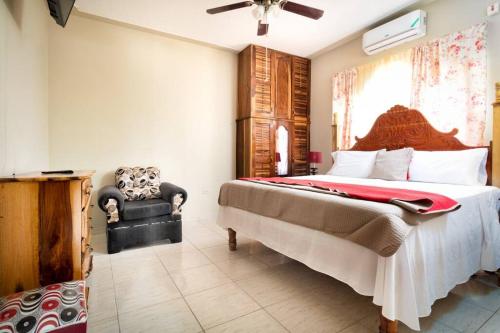 a bedroom with a large bed and a chair at Cozy Locale - Gold in Port Antonio