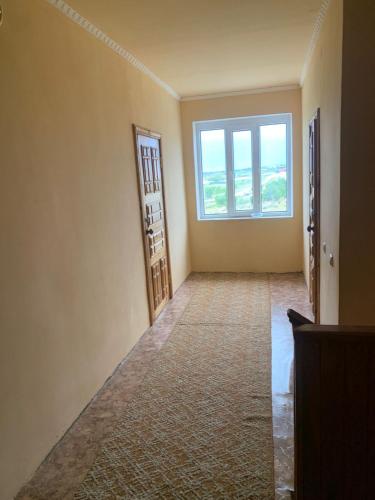 an empty room with a large window and a hallway at Guest House in Cholpon-Ata