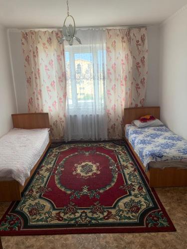 a bedroom with two beds and a rug on the floor at Guest House in Cholpon-Ata