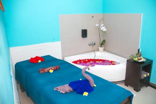 a room with a bath tub and two beds with clothes at Abian Harmony Hotel in Sanur