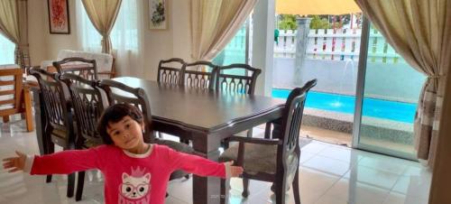 a young child sitting at a dining room table at Murni Inn Pulasan in Guar Chempedak