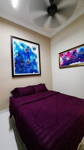 a bedroom with a purple bed and two pictures on the wall at Murni Inn Pulasan in Guar Chempedak