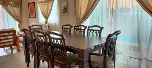 a dining room with a wooden table and chairs at Murni Inn Pulasan in Guar Chempedak