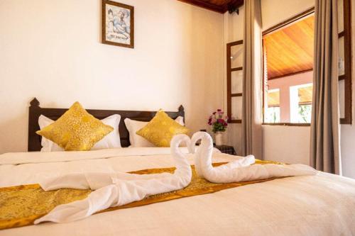 due cigni sono seduti sopra un letto di Dear Villa House a Luang Prabang