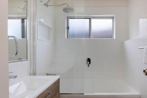 a white bathroom with a sink and a shower at Reflections Bermagui - Holiday Park in Bermagui