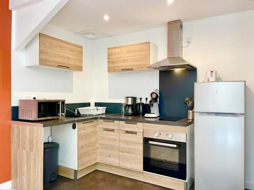 - une cuisine avec des placards en bois et un réfrigérateur blanc dans l'établissement Le Terra Cotta - Lumineux - Tout Confort - proche gare - NOUVEAU, à Lorient