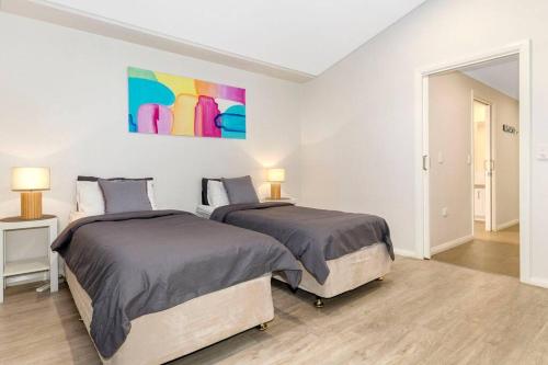 a bedroom with two beds and a painting on the wall at Aqua21 @ Cape Villas Dunsborough in Dunsborough