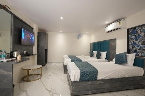 a hotel room with two beds and a flat screen tv at MEGH INN in Navi Mumbai