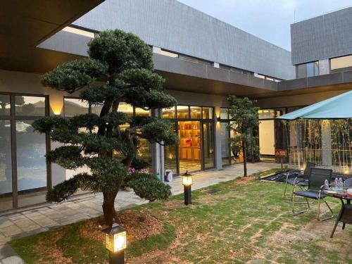 a tree in a yard in front of a building at SongShan Lake PingShang Serviced Hotel in Huangcaolang
