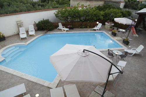 a large swimming pool with an umbrella and chairs at Il Quadrifoglio in Trapani