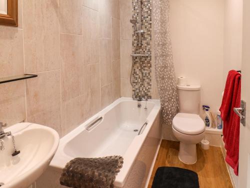 a bathroom with a tub and a toilet and a sink at Cupid's Cottage in Bessingby