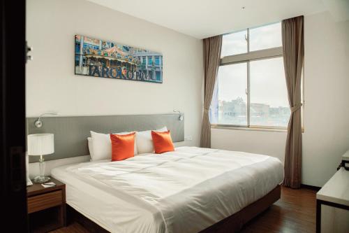 高雄的住宿－華園大飯店草衙館，卧室配有带橙色枕头的大型白色床