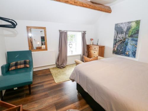 1 dormitorio con cama, silla y espejo en 2 Carr Farm Close, en Glossop