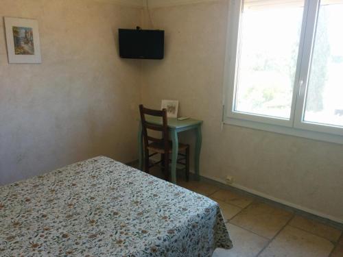 a bedroom with a bed and a table and a window at Hôtel Restaurant l'Agachon in Albaron