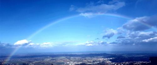 een regenboog in de lucht boven een stad bij San Marino Skyline - Dante in Valdragone