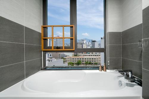 a bath tub in a bathroom with a window at Monalisa Luxury Hotel in Da Nang