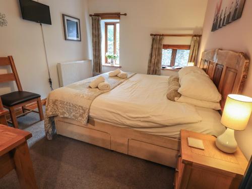 een slaapkamer met een bed en een tafel met een lamp bij Tullythwaite Garth in Crosthwaite