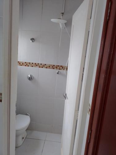 a white bathroom with a toilet and a shower at Loft no centro de Araxá in Araxá