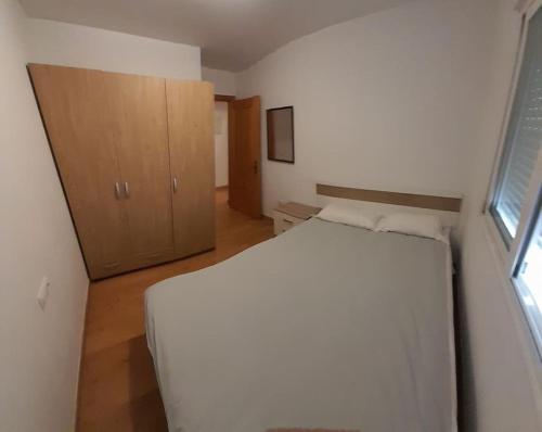 1 dormitorio con cama blanca y armario de madera en 2F, Aire Acondic, 80m2, 2 dormitorios, 4 huéspedes, WIFI GRATIS, en La Línea de la Concepción