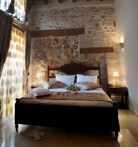 a bedroom with a bed with a stone wall at Antica Dimora Suites in Rethymno Town