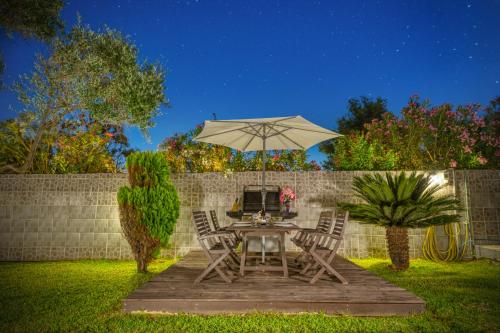 a table and chairs with an umbrella in a yard at Villa Angela in Ágios Matthaíos