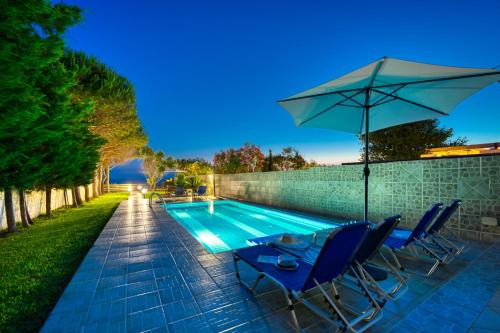 a swimming pool with a table and an umbrella at Villa Angela in Ágios Matthaíos