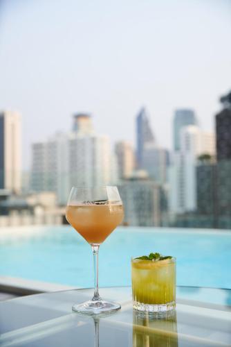 a drink in a glass sitting on top of a table at Public House Bangkok, a Member of Design Hotels in Bangkok