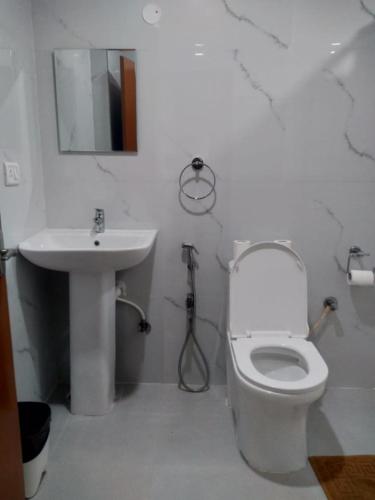 a bathroom with a white toilet and a sink at Sathya Sai Sankalp Hotel in Puttaparthi