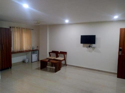 a room with a table and a tv on a wall at Sathya Sai Sankalp Hotel in Puttaparthi
