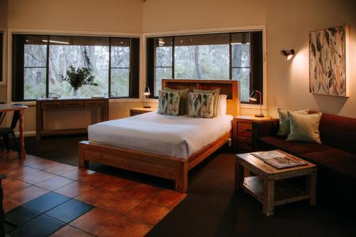 1 dormitorio con cama, sofá y ventanas en Federation Gardens & Possums Hideaway, en Blackheath