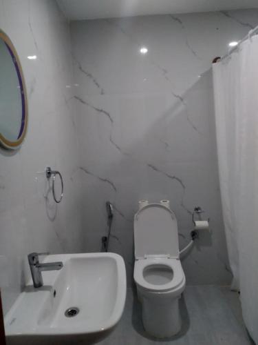 a white bathroom with a toilet and a sink at Sathya Sai Sankalp Hotel in Puttaparthi