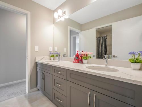 La salle de bains est pourvue de 2 lavabos et d'un grand miroir. dans l'établissement A cozy 3 bedroom new house with 2 living rooms, à Edmonton