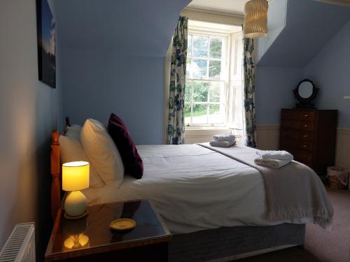ein Schlafzimmer mit einem Bett mit einer Lampe und einem Fenster in der Unterkunft Upper West Wing Flat - Tarvit in Cupar