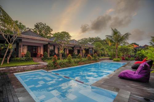 a swimming pool in front of a house at Kanchana Cottages in Uluwatu