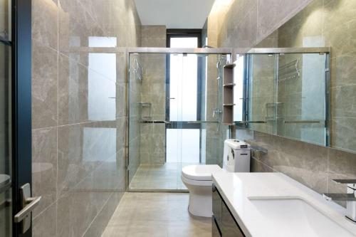 un bagno con wc e doccia in vetro di SongShan Lake PingShang Serviced Hotel a Huangcaolang