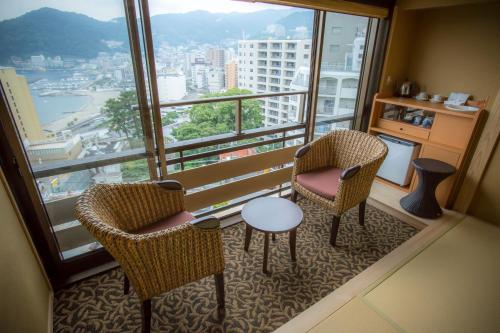 a room with two chairs and a table and a large window at Yuyado Ichibanchi in Atami
