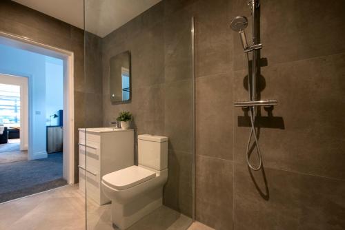 a bathroom with a toilet and a glass shower at Preston Apartments in Preston