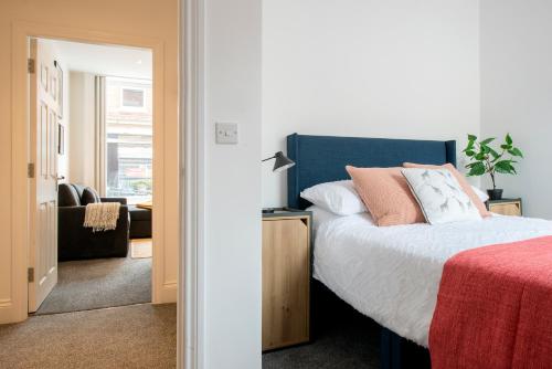 a bedroom with a bed with a blue headboard at Preston Apartments in Preston