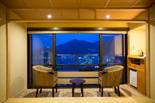 a room with two chairs and a large window at Yuyado Ichibanchi in Atami