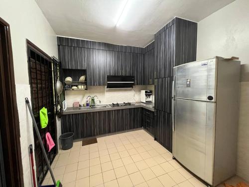 eine Küche mit einem Kühlschrank aus Edelstahl und Holzschränken in der Unterkunft Netflix Wifi (3 Rooms) Homestay Kak Nad Saujana Utama in Sungai Buloh