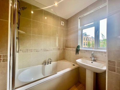 La salle de bains est pourvue d'une baignoire et d'un lavabo. dans l'établissement Family home in Hampshire - Sleeps up to 9 people with 3 parking spaces, à Winchester