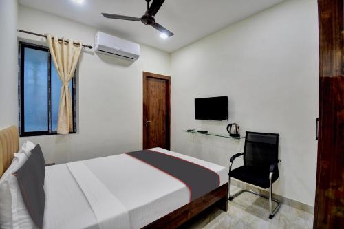 Hotel G.N Palace في كولْكاتا: غرفة نوم بسرير وتلفزيون وكرسي