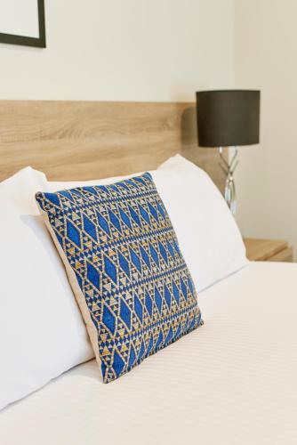 a white bed with a blue and white pillow on it at The Dingley Hotel in Dingley