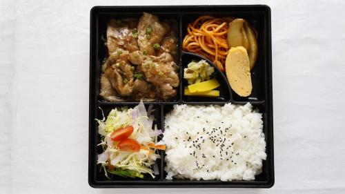a black plate of food with rice and vegetables at 時津ヤスダオーシャンホテル in Togitsu