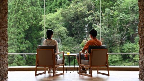 duas pessoas sentadas numa mesa a olhar pela janela em Hotel Shidotaira em Hanamaki