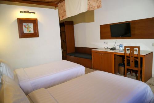 a room with two beds and a desk and a television at The Lagoon Bali Pool Hotel and Suites in Legian