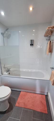 a bathroom with a white tub and a toilet at Modern and spacious Swansea centre apartment in Swansea