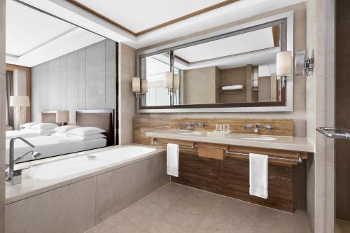 a bathroom with a tub and a sink and a mirror at Sheraton Qiandao Lake Resort in Chun'an